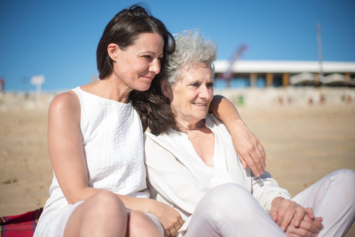 Adult daughter with her arm around her older mother outdoors