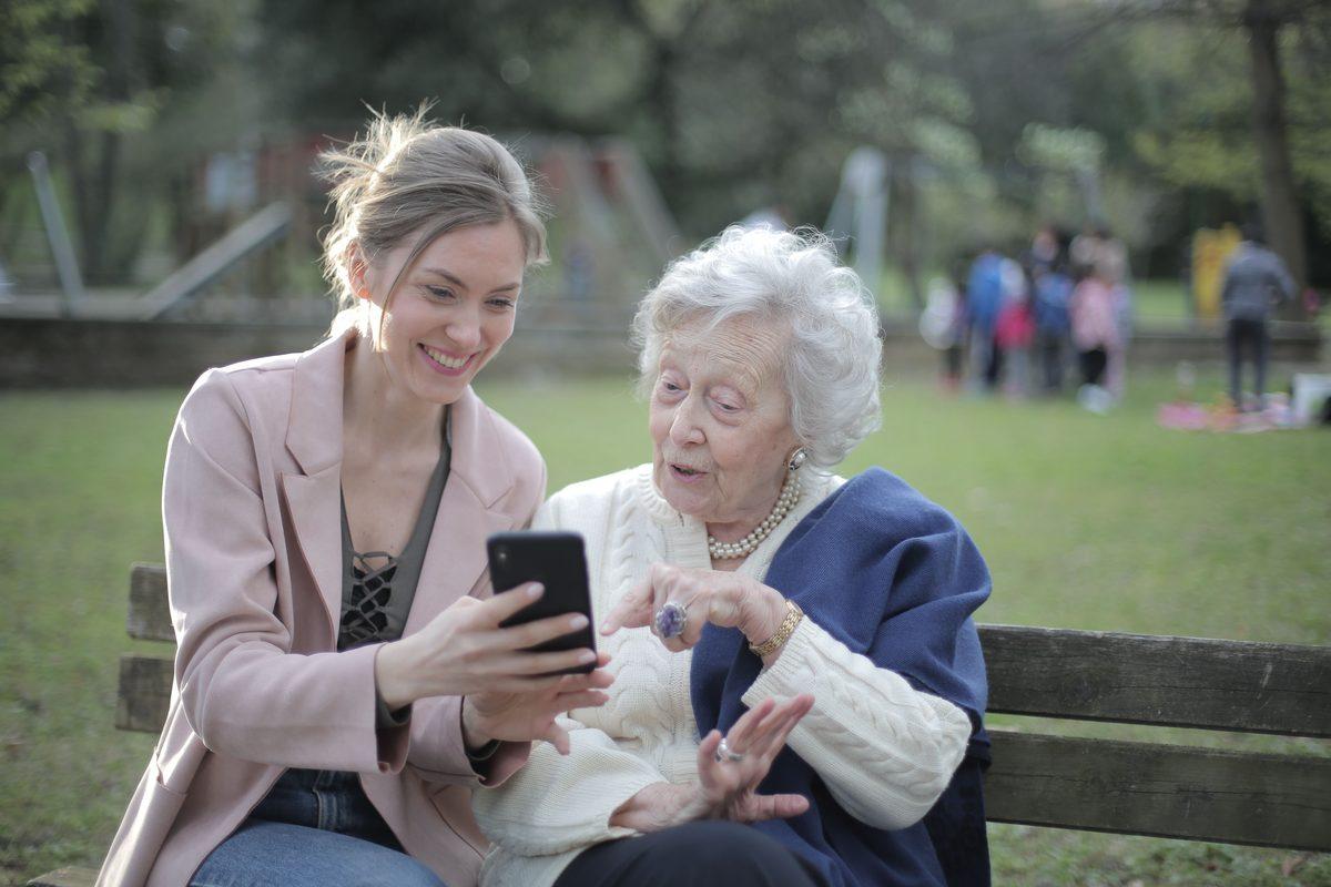 Adult daughter showing her older mother something on a phone